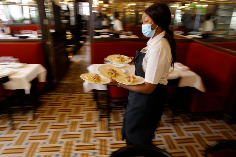 &copy; Reuters. FILE PHOTO: A waiter serves dishes in a dining room at Au Petit Riche restaurant in Paris as cafes, bars and restaurants reopen indoor dining rooms with a fitted gauge and health protocol after closing down for months amid the coronavirus disease (COVID-1