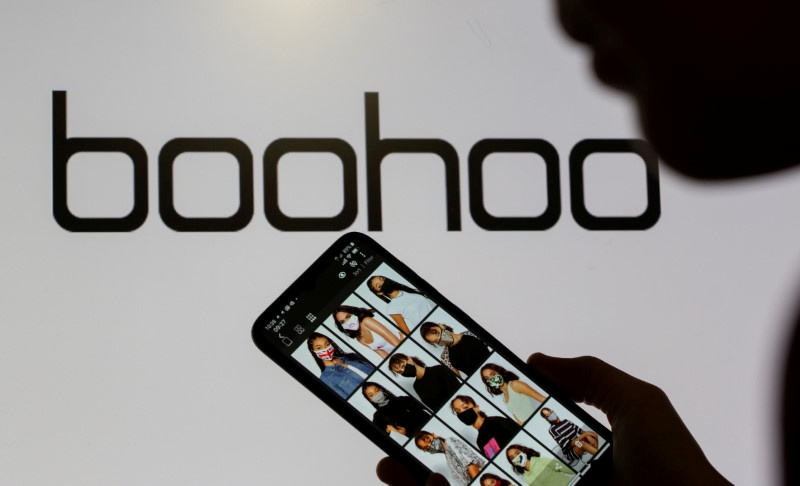 &copy; Reuters. FILE PHOTO: A woman poses with a smartphone showing the Boohoo app in front of the Boohoo logo on display in this illustration taken September 30, 2020. REUTERS/Dado Ruvic