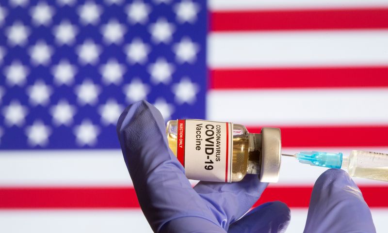 &copy; Reuters. A woman holds a small bottle labeled with a "Coronavirus COVID-19 Vaccine" sticker and a medical syringe in front of displayed USA flag in this illustration taken, October 30, 2020. REUTERS/Dado Ruvic
