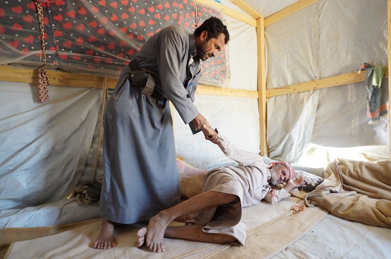 &copy; Reuters. عبد الله يساعد والده محمد الحرملي الذي يعاني من مشكلة في العمود الفقري في مخيم للنازحين في مأرب باليمن يوم الثالث من نوفمبر تشرين الثاني 2021. 
