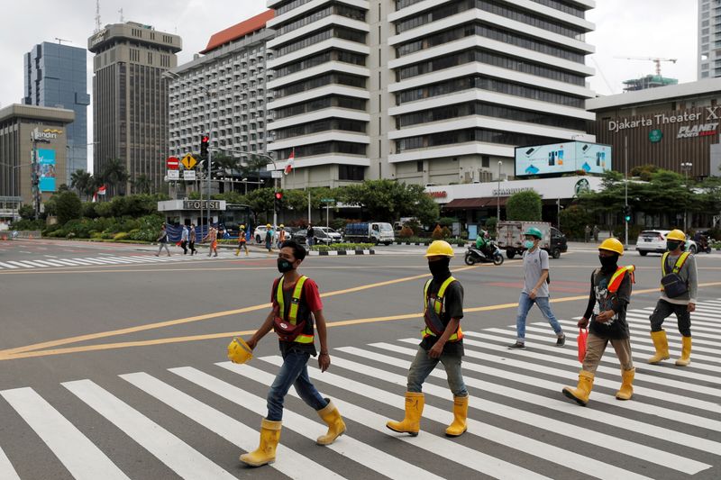 © Reuters. FILE PHOTO: Construction workers wearing protective masks to prevent the spread of the coronavirus disease (COVID-19) cross a main road in Jakarta, Indonesia, February 5, 2021. REUTERS/Willy Kurniawan