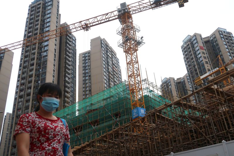 &copy; Reuters. FILE PHOTO: A woman wearing a face mask walks past a construction site near residential buildings in Shenzhen, following the novel coronavirus disease (COVID-19) outbreak, Guangdong province, China May 17, 2020. REUTERS/Martin Pollard