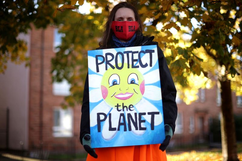 &copy; Reuters. FILE PHOTO: An Extinction Rebellion activist carries a sign during a protest, as the UN Climate Change Conference (COP26) takes place, in Glasgow, Scotland, Britain, November 4, 2021. REUTERS/Hannah McKay