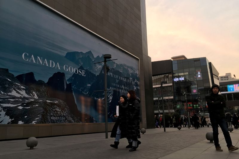 &copy; Reuters. FILE PHOTO: People walk past an advertisement near the flagship store of Canadian luxury parka maker Canada Goose, in Sanlitun area of Beijing, China December 31, 2018. REUTERS/Martin Pollard/File Photo