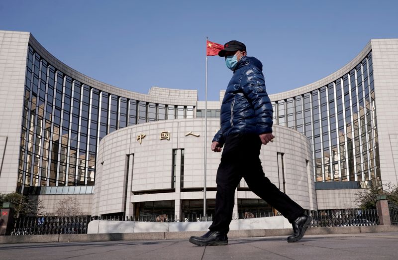 &copy; Reuters. FILE PHOTO: A man wearing a mask walks past the headquarters of the People's Bank of China, the central bank, in Beijing, China, February 3, 2020. REUTERS/Jason Lee