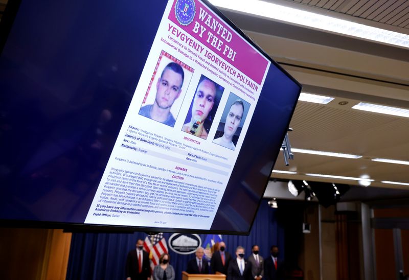 © Reuters. A 'wanted' poster showing Russian national Yevgeniy Polyanin is seen as U.S. Attorney General Merrick Garland announces charges over a July ransomware attack on an American company, as FBI Director Christopher Wray, Deputy Attorney General Lisa Monaco and Deputy Treasury Secretary Wally Adeyemo standby during a news conference at the Justice Department in Washington, U.S., November 8, 2021. REUTERS/Jonathan Ernst