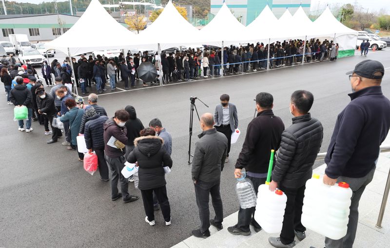 &copy; Reuters. 韓国でディーゼル車の運行や工場の操業に必要な尿素水が不足している。尿素水を求めて並ぶ人々、益山で９日撮影。聯合ニュース提供（２０２１年　ロイター）