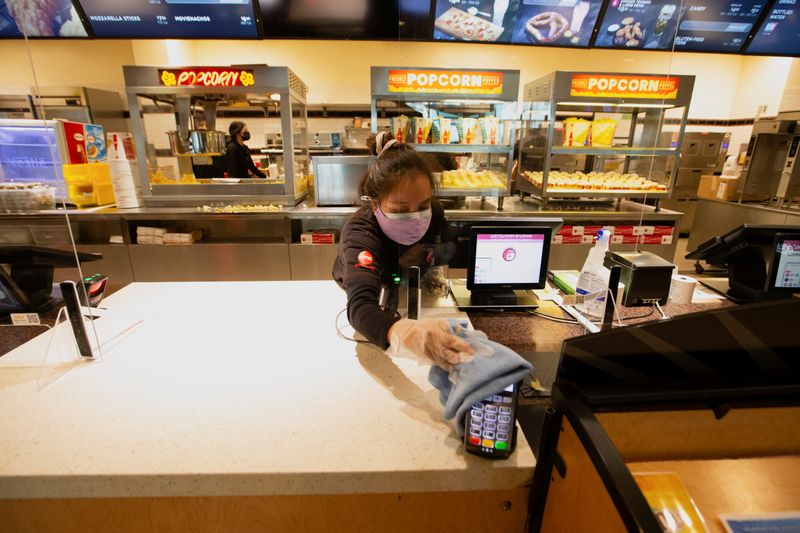 &copy; Reuters. FILE PHOTO: A member of the staff sanitizes a credit card machine at a AMC theatre on reopening day during the outbreak of the coronavirus disease (COVID-19), in Burbank, California, U.S., March 15, 2021.  REUTERS/Mario Anzuoni