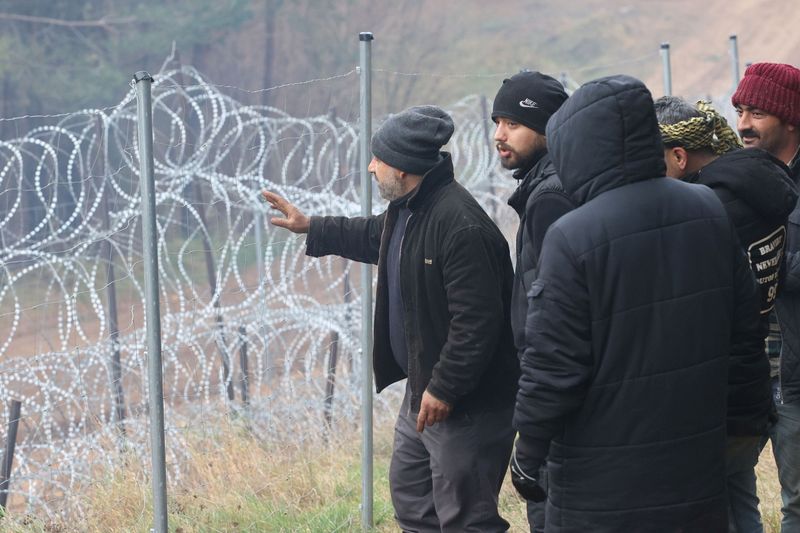 &copy; Reuters. مهاجرون يتجمعون بالقرب من سلك حدودي شائك في محاولة لعبور الحدود الى بولندا من منطقة جرودنو في روسيا البيضاء يوم الثلاثاء. صورة لرويترز.