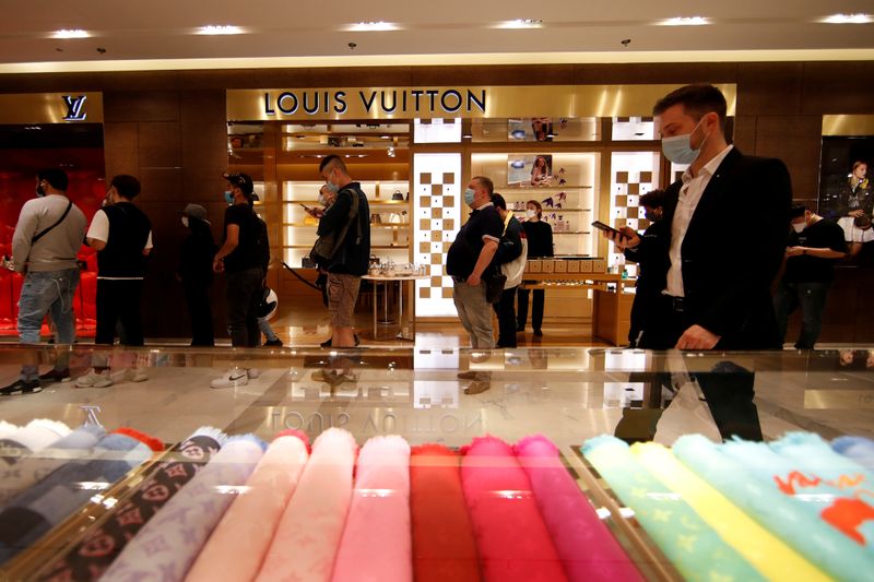 &copy; Reuters. FILE PHOTO: Clients, wearing protective face masks, queue in line in front of a Louis Vuitton shop inside the department store Le Printemps Haussmann in Paris following the outbreak of the coronavirus disease (COVID-19) in France, May 28, 2020. REUTERS/Go