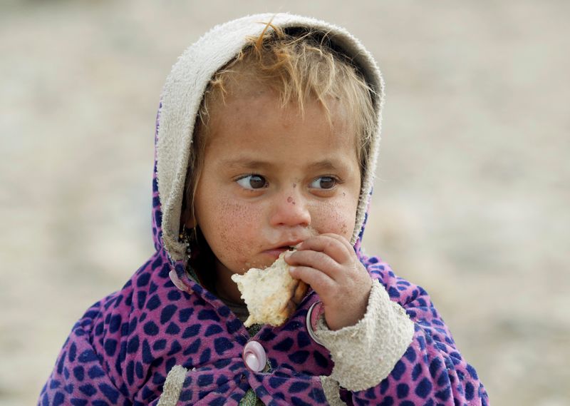 &copy; Reuters. طفل أفغاني نازح يأكل خارج خيمة في صحراء في منطقة خوجياني في إقليم ننكرهار بأفغانستان. صورة من أرشيف رويترز.