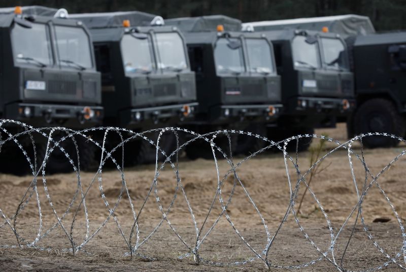 &copy; Reuters. Trucks from 16th Pomeranian Mechanised Division are seen behind a barbed wire at the temporary camp during migrant crisis on Belarusian - Polish border near Siemianowka, Poland, November 12, 2021. REUTERS/Kacper Pempel