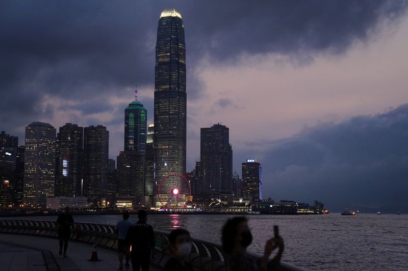 &copy; Reuters. FILE PHOTO: A woman takes pictures in front of high-rise buildings in the Central financial district after sunset in Hong Kong, China March 30, 2021. REUTERS/Lam Yik