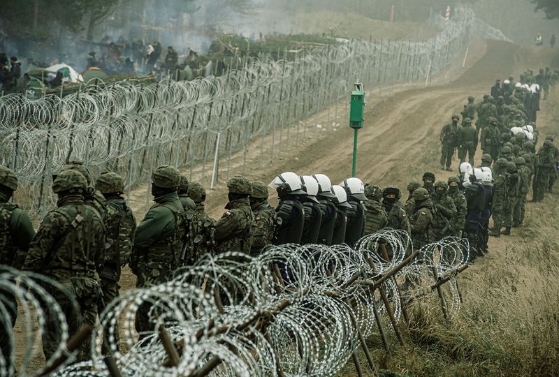 &copy; Reuters. Des soldats et des policiers polonais observent des migrants à la frontière entre la Pologne et la Biélorussie près de Kuznica, en Pologne, sur cette photo publiée par les Forces de défense territoriale. Un groupe d'une cinquantaine de migrants est 