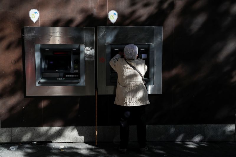 &copy; Reuters. A woman uses a Caixabank branch ATM machine displaying logos of both Caixabank and Bankia banks in Madrid, Spain, November 10, 2021. REUTERS/Susana Vera