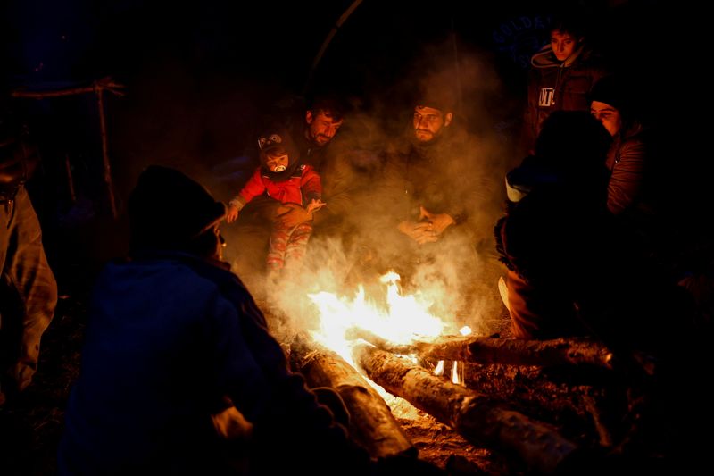 &copy; Reuters. Migrants gather around a fire in a makeshift camp on the Belarusian-Polish border in the Grodno region, Belarus November 14, 2021. Picture taken November 14, 2021. Oksana Manchuk/BelTA/Handout via REUTERS 