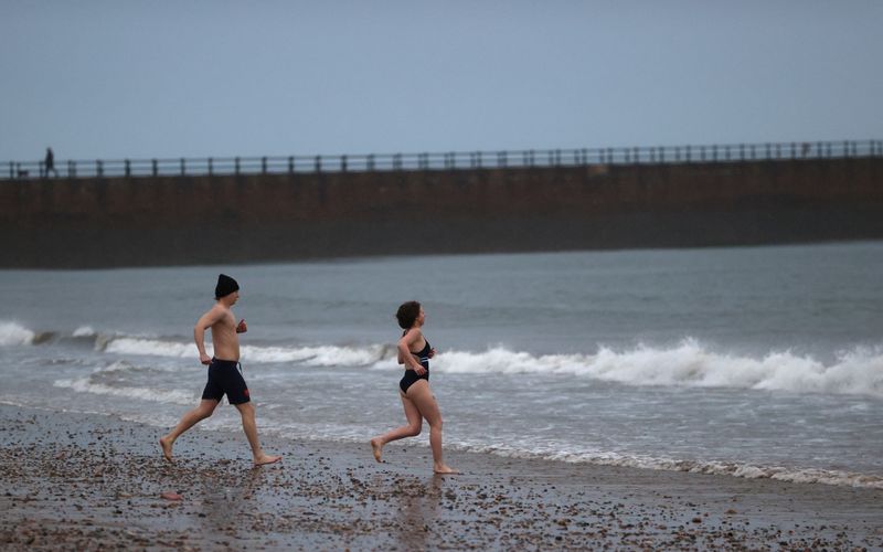 © Reuters. FILE PHOTO: People walk on a beach to enter the North Sea on New Year's Day amid the outbreak of the coronavirus disease (COVID-19), at Rocker in Sunderland, Britain January 1, 2021. REUTERS/Lee Smith