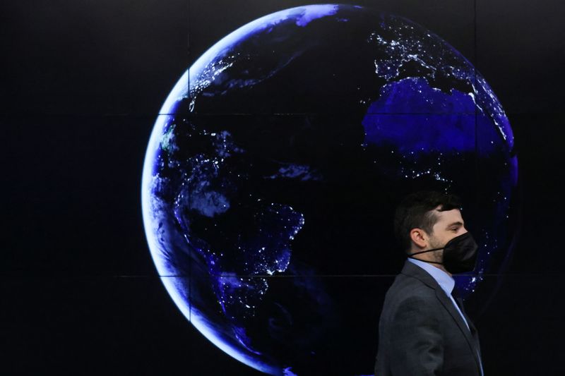 &copy; Reuters. FILE PHOTO: A delegate walks past a picture showing the Earth at night at the UN Climate Change Conference (COP26) in Glasgow, Scotland, Britain, November 11, 2021. REUTERS/Yves Herman