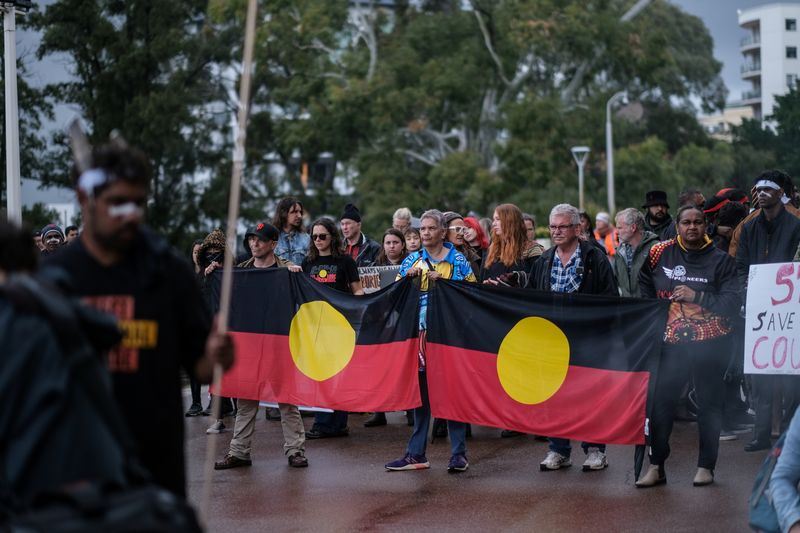 &copy; Reuters. FILE PHOTO: Aboriginal groups' members carry Australian Aboriginal flags while taking part in a march against what they say is a lack of detail and consultation on new heritage protection laws, after the Rio Tinto mining group destroyed ancient rock shelt
