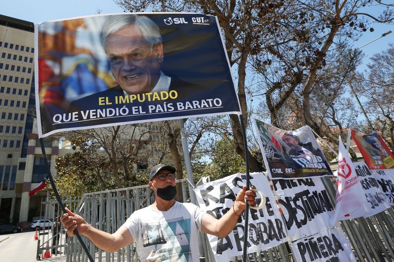 © Reuters. Un manifestant tient une banderole représentant le président chilien Sebastian Pinera et l'inscription 