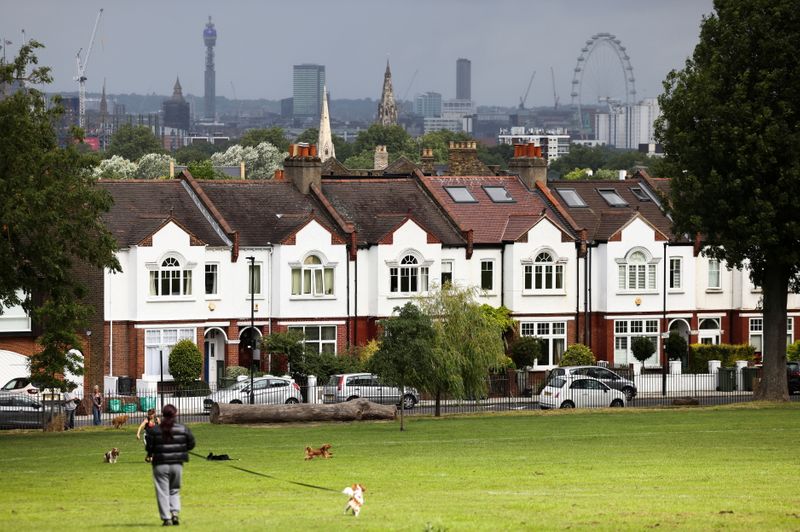 &copy; Reuters. FILE PHOTO: A person walks with a dog in front of a row of residential housing in south London, Britain, August 6, 2021. REUTERS/Henry Nicholls