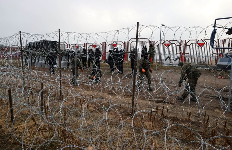 &copy; Reuters. FILE PHOTO: A view from a migrants' camp shows Polish law enforcement officers, who stand guard behind a fence on the Belarusian-Polish border in the Grodno region, Belarus November 17, 2021. Maxim Guchek/BelTA/Handout via REUTERS 