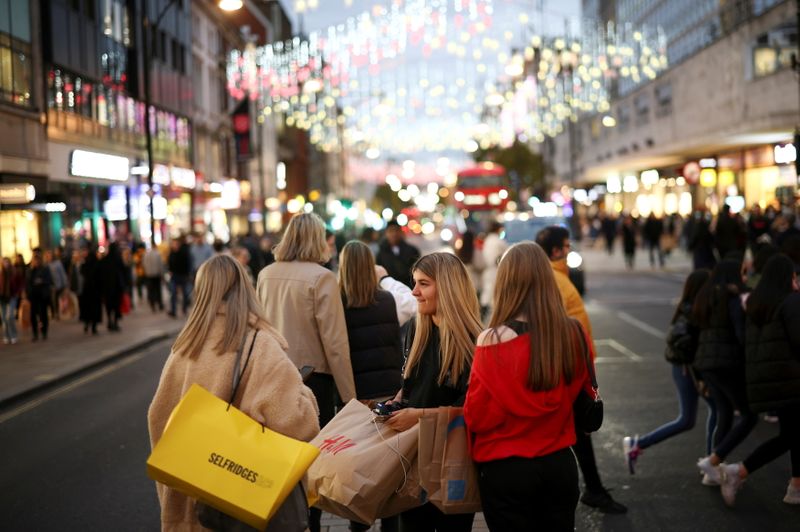© Reuters. FILE PHOTO: People with shopping bags walk along Oxford Street illuminated with Christmas lights in London, Britain, November 13, 2021. REUTERS/Henry Nicholls/File Photo