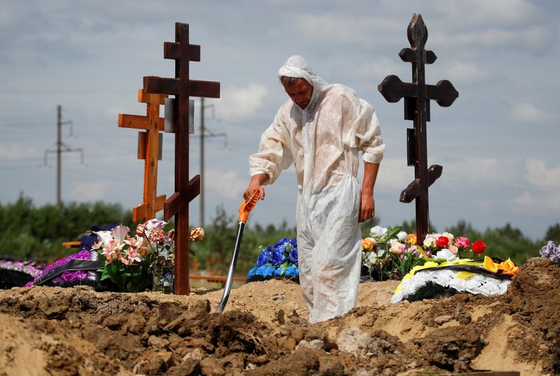 &copy; Reuters. A grave digger wearing personal protective equipment (PPE) as a preventive measure against the coronavirus disease (COVID-19) buries a person at a graveyard on the outskirts of Saint Petersburg, Russia June 25, 2021. REUTERS/Anton Vaganov