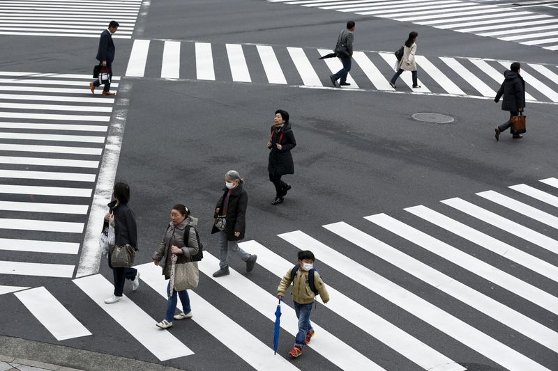 &copy; Reuters. People cross a street in the Ginza shopping district in Tokyo, Japan, March 24, 2016. Japan's consumer inflation was flat in the year to February as low energy costs and weak consumption put a lid on price growth, keeping the central bank under pressure t