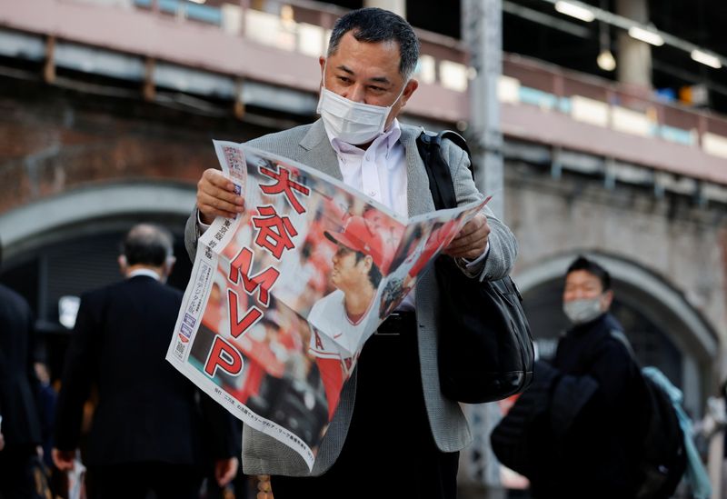 © Reuters. A man reads an extra edition of a newspaper, reporting Japan's Shohei Ohtani of the Los Angeles Angels was named Most Valuable Player of Major League Baseball's American League, in Tokyo, Japan November 19, 2021. REUTERS/Issei Kato