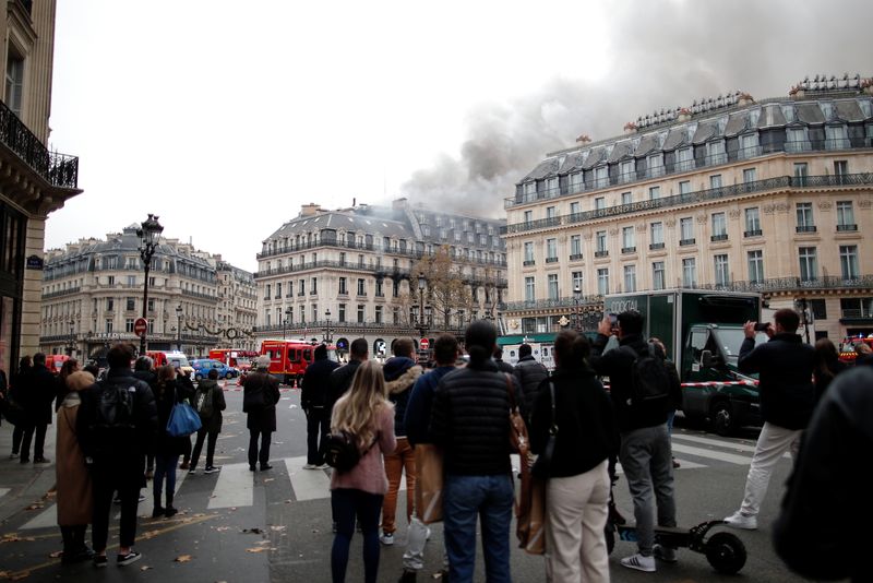 &copy; Reuters. مارة ينظرون إلى الدخان المتصاعد من حريق اندلع في بناية بالقرب من ميدان الأوبرا في باريس يوم السبت. تصوير: بنوا تيسيير - رويترز.
