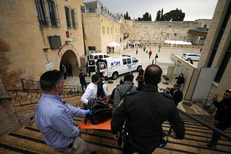 &copy; Reuters. أفراد من قوات الأمن الإسرائيلية يحملون جثة قرب الحائط الغربي بالقدس المحتلة بعد واقعة إطلاق النار يوم الأحد. تصوير عمار عوض-رويترز.