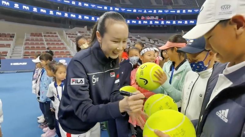 © Reuters. Chinese tennis player Peng Shuai signs large-sized tennis balls at the opening ceremony of Fila Kids Junior Tennis Challenger Final in Beijing, China November 21, 2021, in this screen grab obtained from a social media video. TWITTER @QINGQINGPARIS via REUTERS 