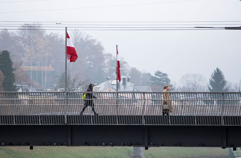 © Reuters. People pass by Austrian flags during the coronavirus disease (COVID-19) outbreak, as Austria's government imposed a general lockdown from Monday, in Salzburg, Austria, November 22, 2021. REUTERS/Lukas Barth