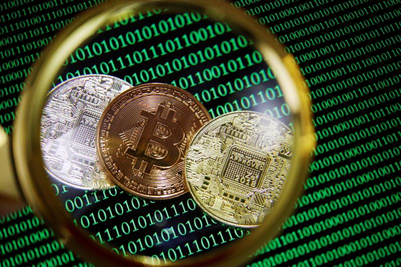 &copy; Reuters. FILE PHOTO: Representations of Bitcoin and other cryptocurrencies on a screen showing binary codes are seen through a magnifying glass in this illustration picture taken September 27, 2021. REUTERS/Florence Lo/Illustration
