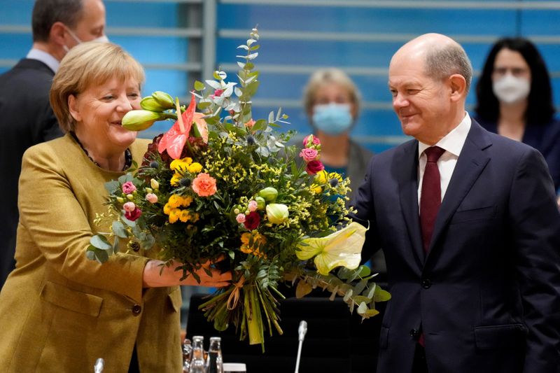 &copy; Reuters. Acting German Chancellor Angela Merkel receives a bouquet from acting German Finance Minister Olaf Scholz prior to the weekly cabinet meeting at the Chancellery in Berlin, Germany, November 24, 2021. Markus Schreiber/Pool via REUTERS