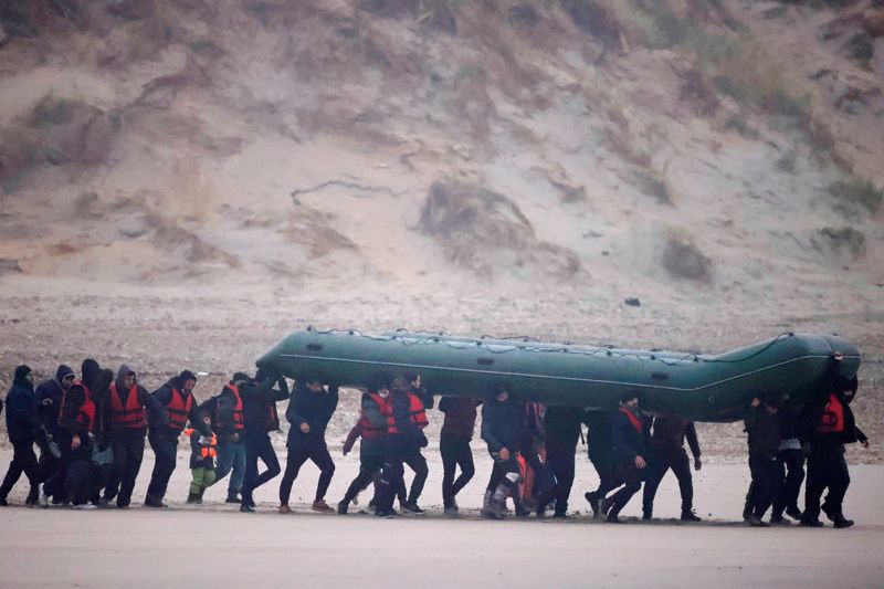 © Reuters. Un grupo de más de 40 migrantes corre en la playa con un bote inflable, para dejar la costa del norte de Francia y cruzar el Canal de la Mancha, cerca de Wimereux, Francia. 24 de noviembre de 2021. REUTERS/Gonzalo Fuentes