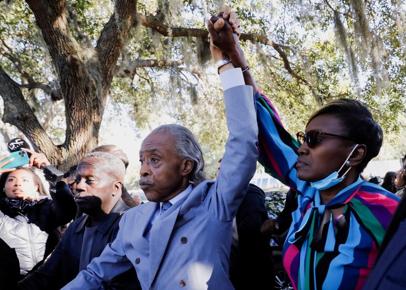 © Reuters. Reverend Al Sharpton and Wanda Cooper-Jones, mother of Ahmaud Arbery, raise their hands outside the Glynn County Courthouse after the jury reached a guilty verdict in the trial of William 