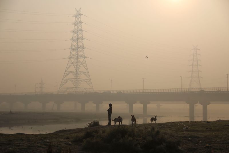 &copy; Reuters. Un hombre de pie en la rivera del río Yamuna en una mañana cubierta por contaminación en Nueva Delhi, India. 19 de noviembre, 2021. REUTERS/Anushree Fadnavis