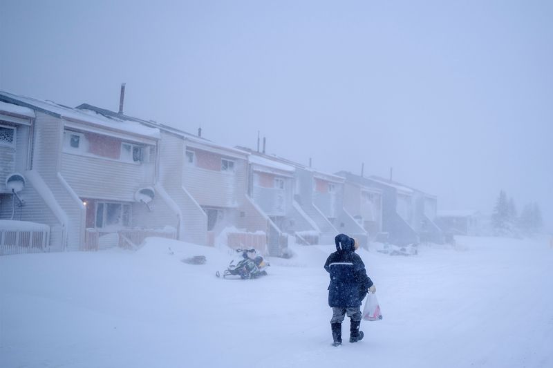 &copy; Reuters. Una mujer camina a casa durante una tormenta luego de hacer compras en Churchill, Manitoba, Canadá. Noviembre 21, 2021.  REUTERS/Carlos Osorio