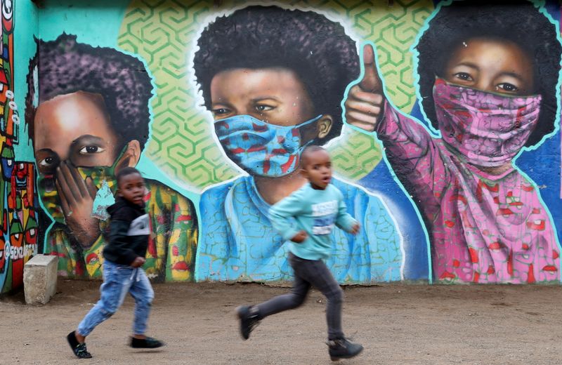&copy; Reuters. FILE PHOTO: Boys run past a mural by Senzart911, of children wearing facemasks amid the coronavirus disease (COVID-19) outbreak, at Soweto's Kliptown, South Africa, October 27, 2021. REUTERS/Siphiwe Sibeko  