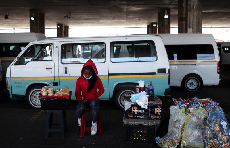 &copy; Reuters. A street hawker looks at her mobile phone as she sits next to her wares after the announcement of a British ban on flights from South Africa because of the detection of a new coronavirus disease (COVID-19) variant, in Soweto, South Africa, November 26, 20