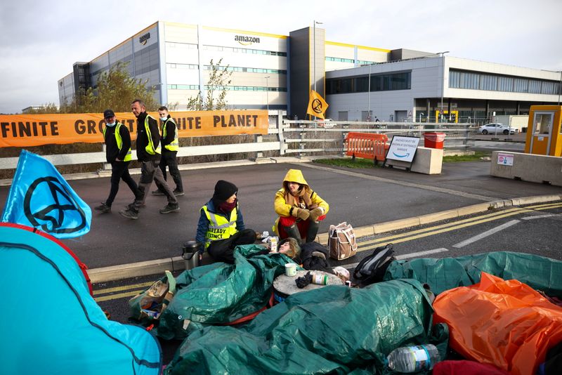 © Reuters. Extinction Rebellion activists are attached to the concrete blocks, as they block a street outside an Amazon fulfilment centre in Tilbury, Essex, Britain, November 26, 2021. REUTERS/Henry Nicholls