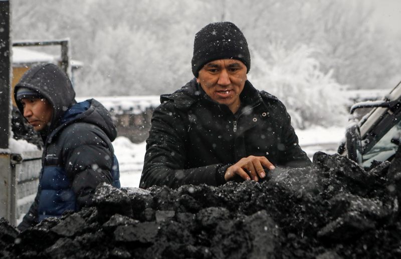 © Reuters. A man stands next to a lorry loaded with coal that people buy at reduced prices to heat their homes amid the energy crunch, in Bishkek, Kyrgyzstan November 26, 2021.  REUTERS/Vladimir Pirogov