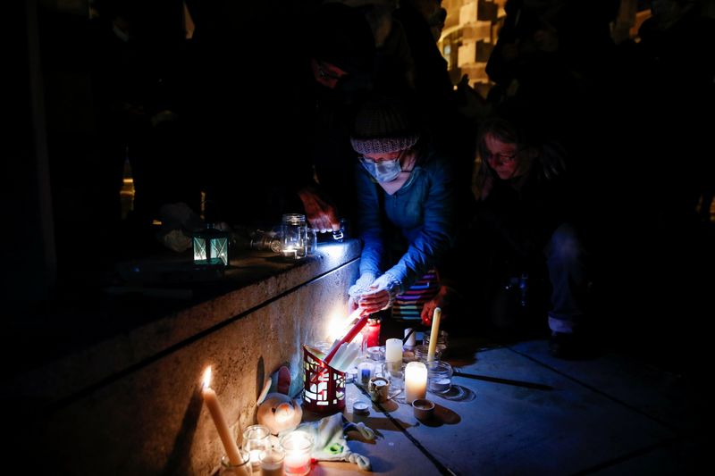 &copy; Reuters. Una persona enciende una vela mientras la gente rinde homenaje a los 27 migrantes que murieron cuando su bote se desinfló cuando intentaban cruzar el Canal de la Mancha, en el Parque Richelieu en Dunkerque, Francia, 25 noviembre 2021.
REUTERS/Johanna Ger