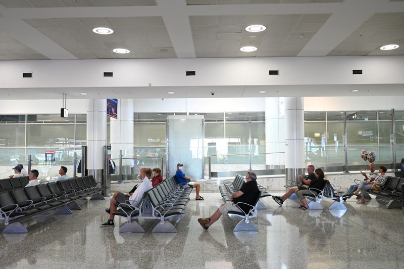 &copy; Reuters. FILE PHOTO: People sit in the arrivals section of the international terminal of Kingsford Smith International Airport in Sydney, Australia, March 21, 2020.  REUTERS/Loren Elliott