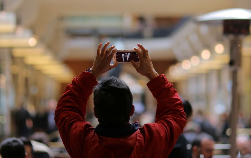 &copy; Reuters. FILE PHOTO: A man takes a mobile phone picture of the windowed ceiling at a shopping mall in Sydney, Australia, July 3, 2017.  REUTERS/Steven Saphore