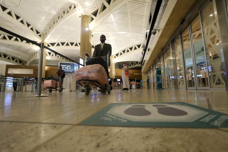 &copy; Reuters. ملصق لتنظيم التباعد الاجتماعي على الأرض ومسافر يضع كمامة ويدفع أمتعته أمامه في مطار الملك خالد الدولي في الرياض يوم 16 مايو أيار 2021. تصوير: أح