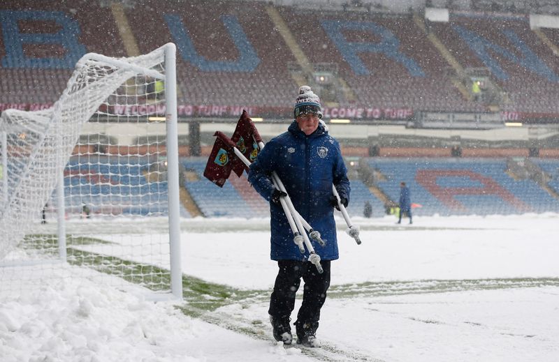 &copy; Reuters. أحد العاملين يسير على الثلوج التي غطت الملعب وأدت إلى تأجيل المباراة بين فريقي بيرنلي وتوتنهام هوتسبير بالدوري الإنجليزي الممتاز لكرة القد
