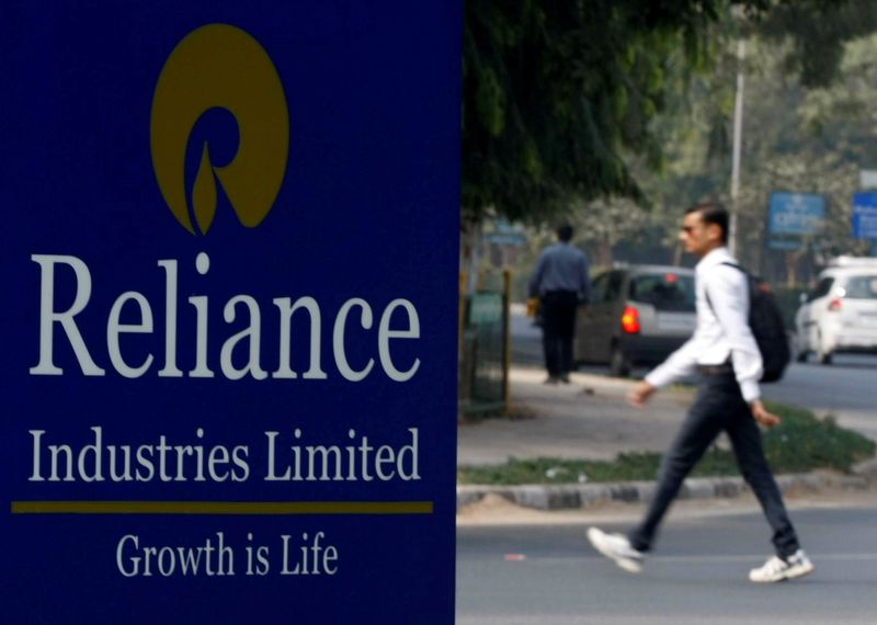 &copy; Reuters. FILE PHOTO: A man walks past a Reliance Industries Limited sign board installed on a road divider in the western Indian city of Gandhinagar January 17, 2014. REUTERS/Amit Dave/File Photo